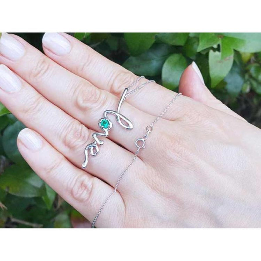 14K white gold "love" script pendant necklace with a round Colombian emerald, held on a hand.