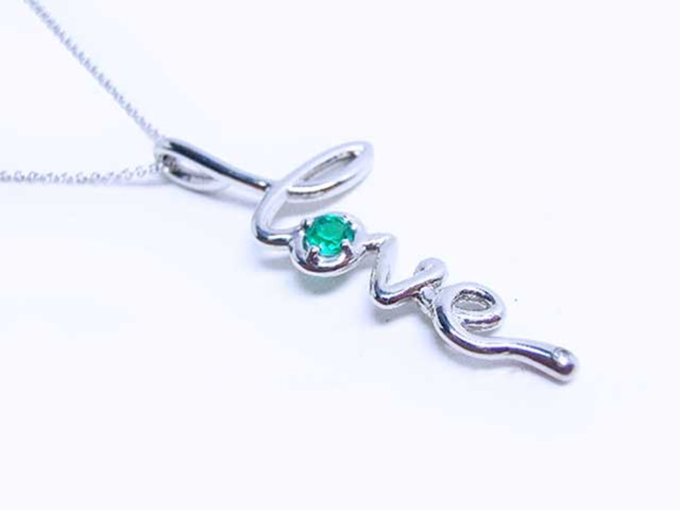 A white gold necklace with a script love pendant featuring an emerald stone on a white background.