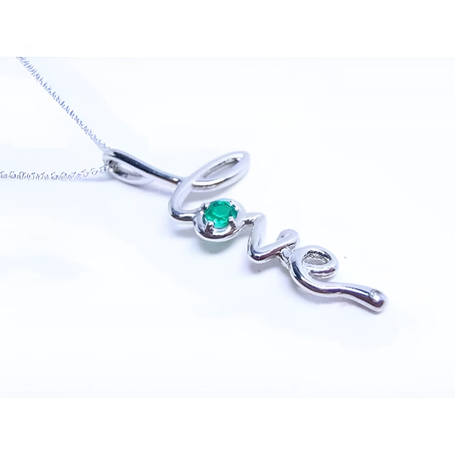 A white gold necklace with a script love pendant featuring an emerald stone on a white background.