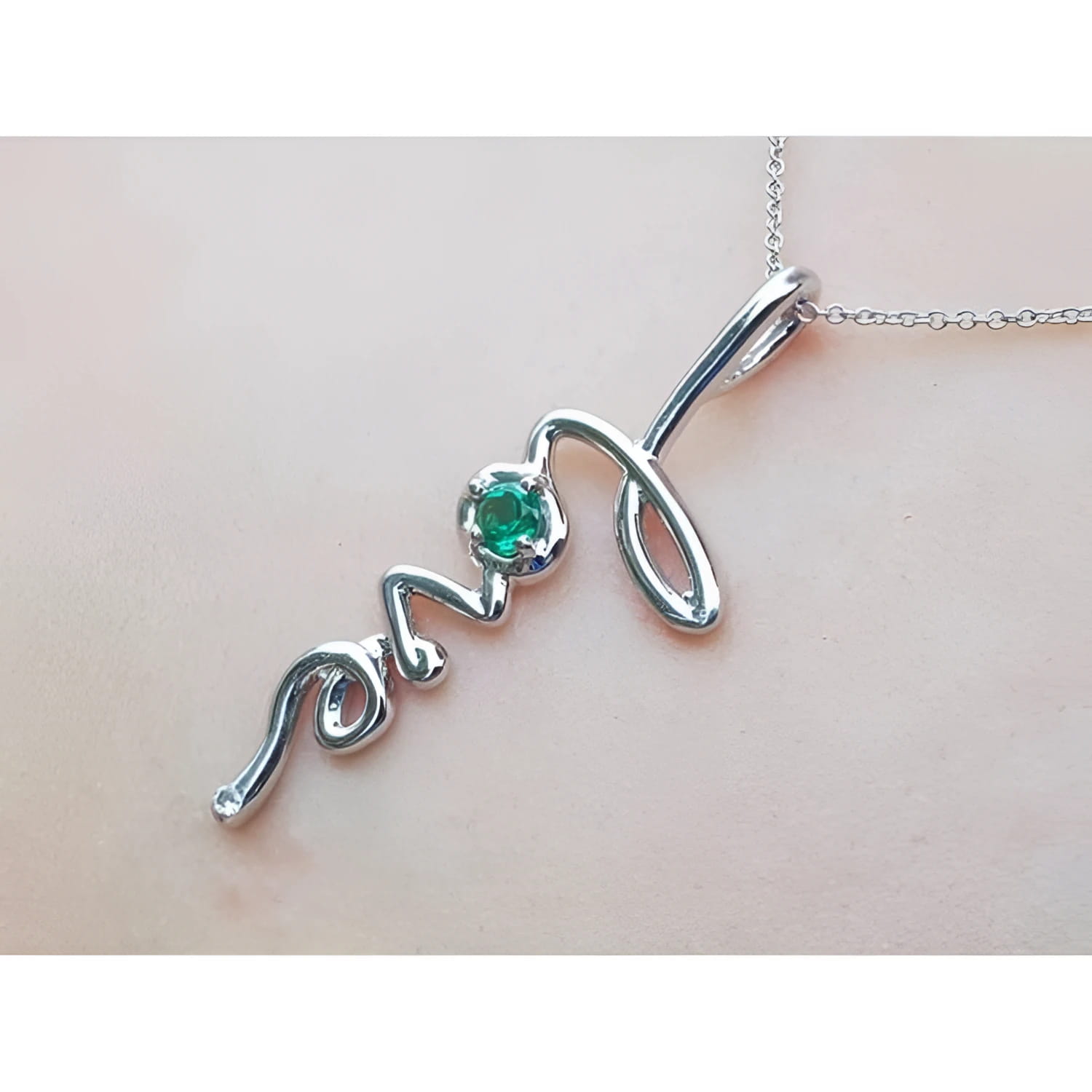 14K white gold "love" script pendant with a round Colombian emerald, on a delicate chain.