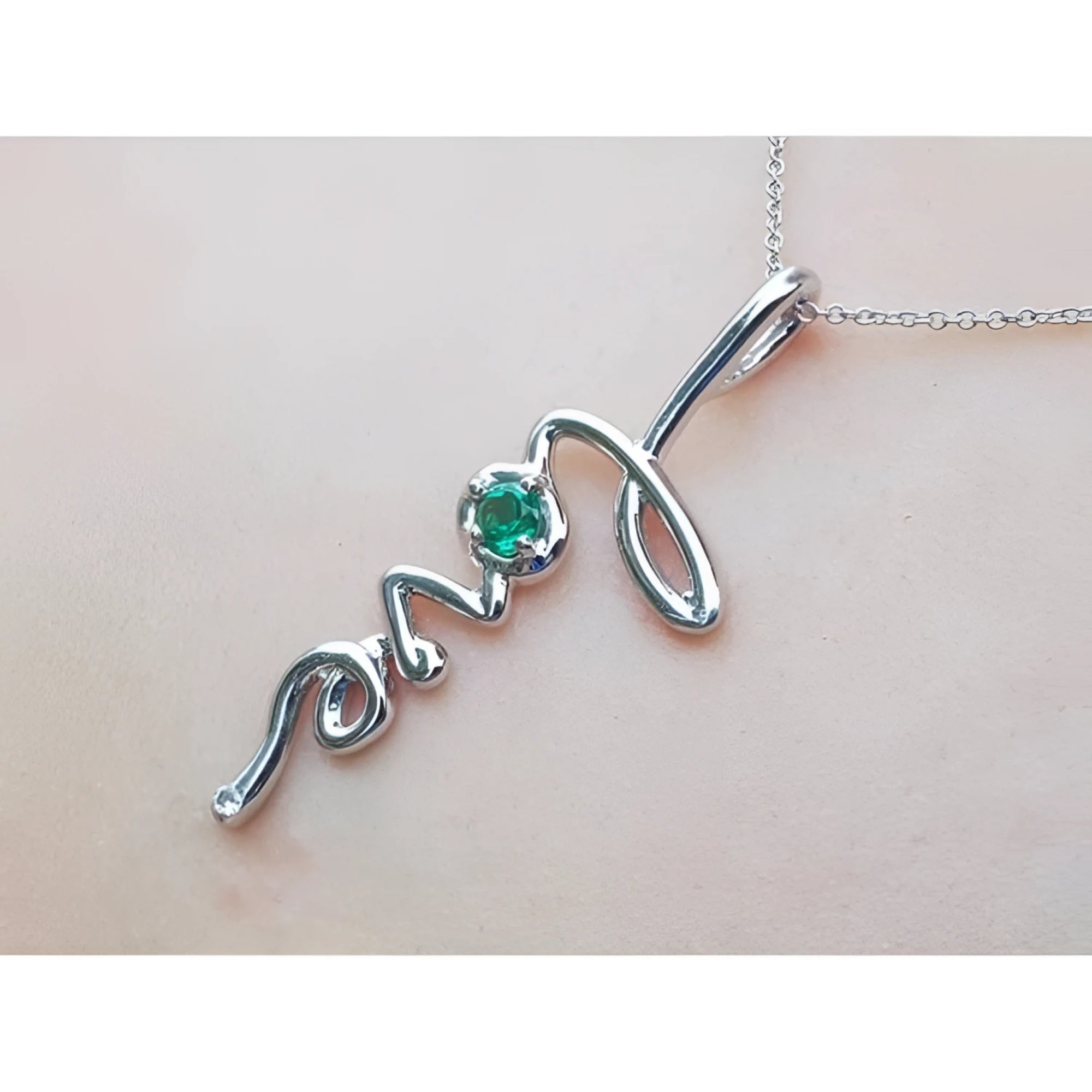 14K white gold "love" script pendant with a round Colombian emerald, on a delicate chain.