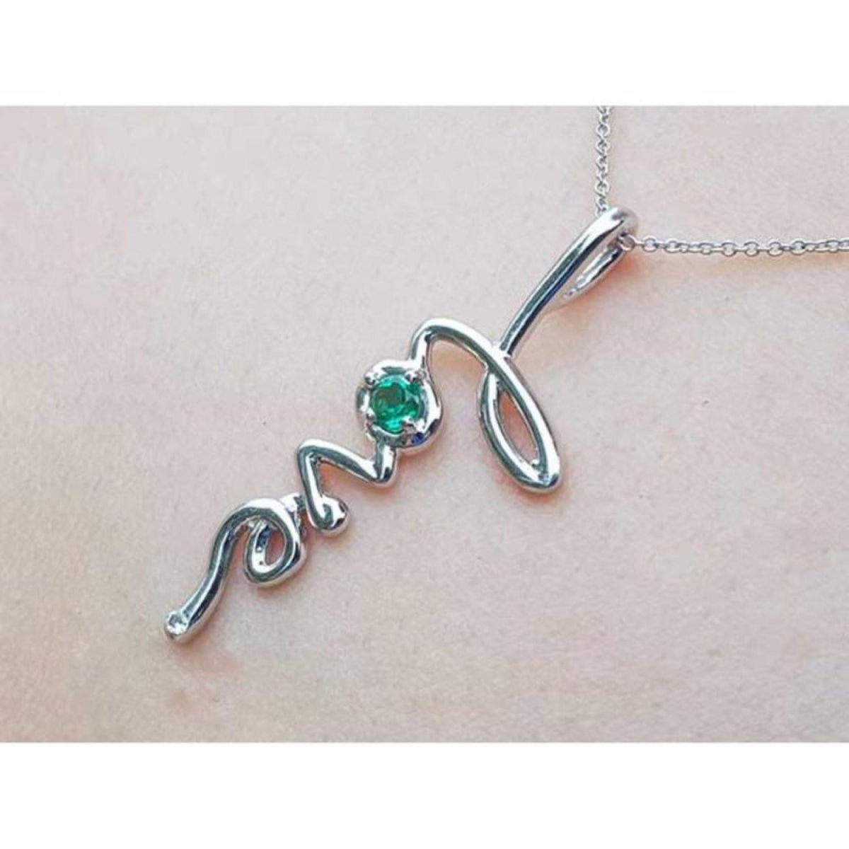 14K white gold "love" script pendant with a round Colombian emerald, on a delicate chain.