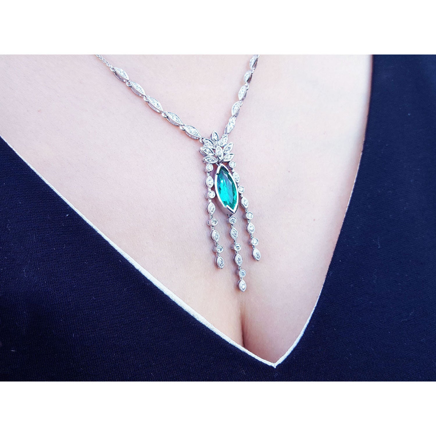 Marquise cut Colombian emerald necklace in 14K white gold with diamond links, worn on a woman's chest.