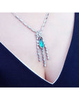 Marquise cut Colombian emerald necklace in 14K white gold with diamond links, worn on a woman's chest.