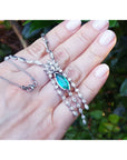 Marquise Colombian emerald and diamond necklace in 14K white gold, held in a hand.