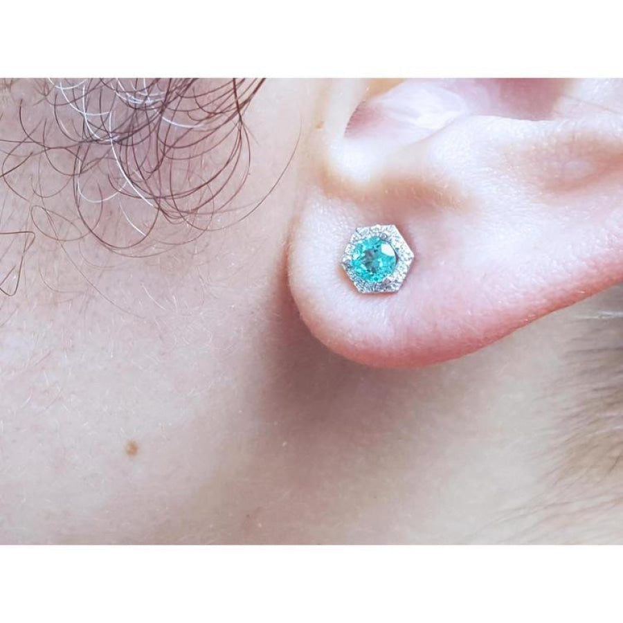 Emerald May birthstone stud earring in 14K white gold with a hexagonal halo on an earlobe.