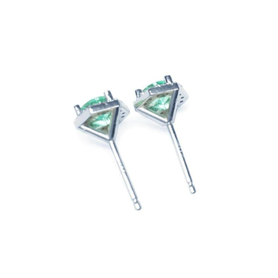 Pair of round cut emerald stud earrings in 14K white gold with push back closures.