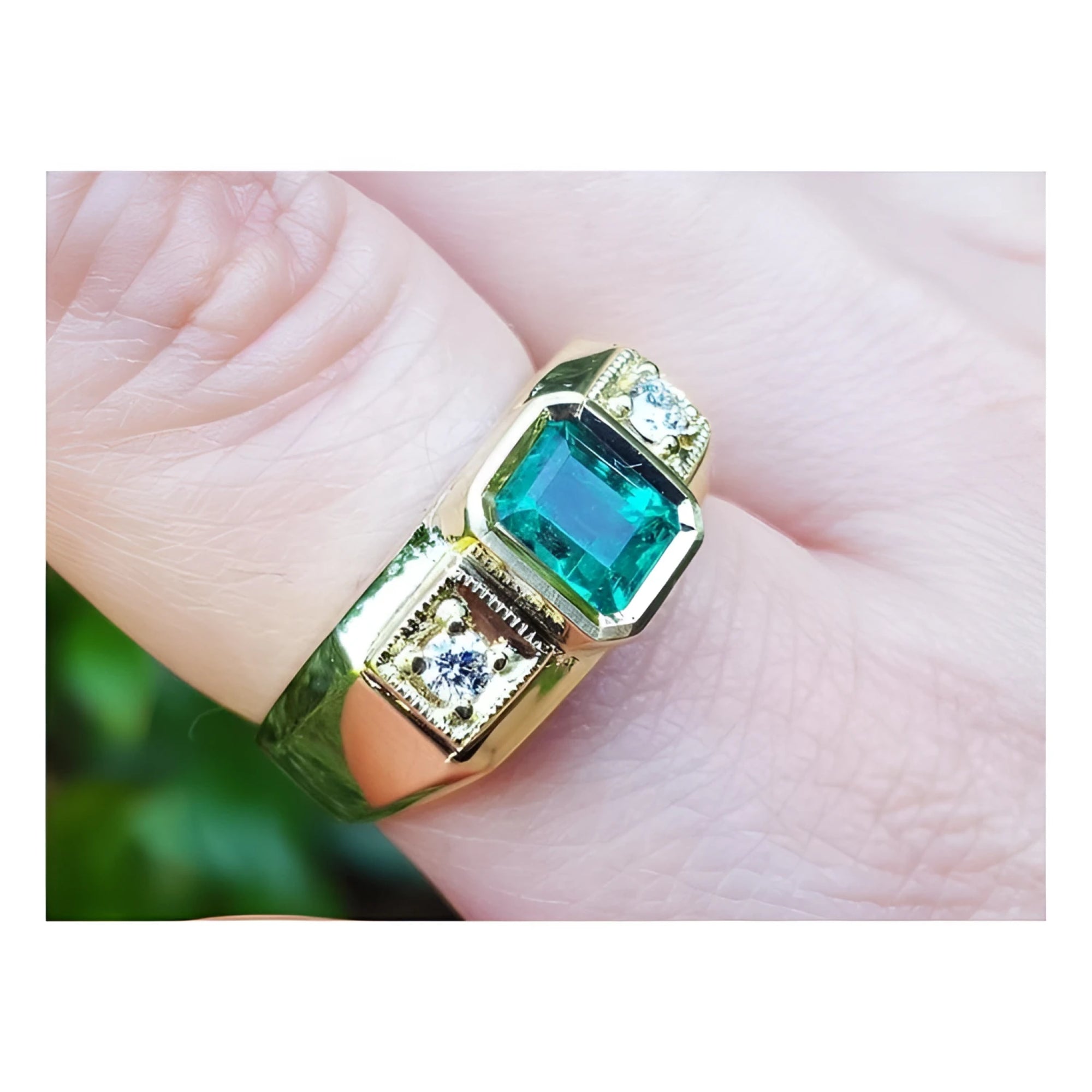 An 18k yellow gold men’s ring featuring a genuine Colombian emerald and side diamonds, elegantly worn on a finger.