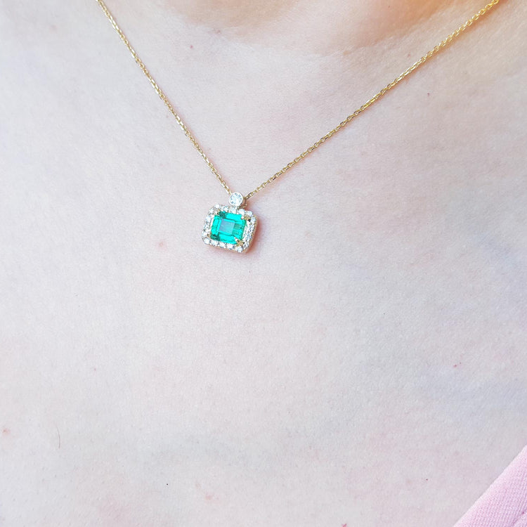 
Emerald-cut emerald necklace east west orientation encircled in a halo of natural diamonds, crafted in 14k yellow gold
