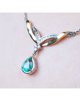 14K white/yellow gold necklace with a deep bluish-green pear-shaped emerald and diamonds.
