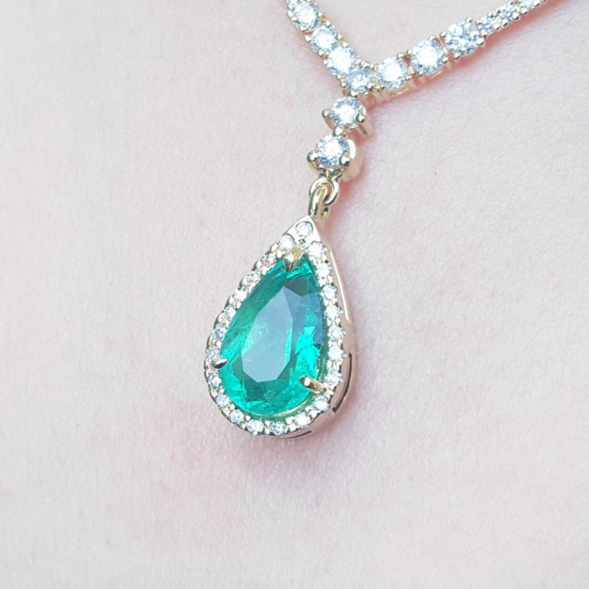 magnification of women&#39;s emerald necklace high quality pear cut in 18k yellow gold, encircled by a halo diamond 