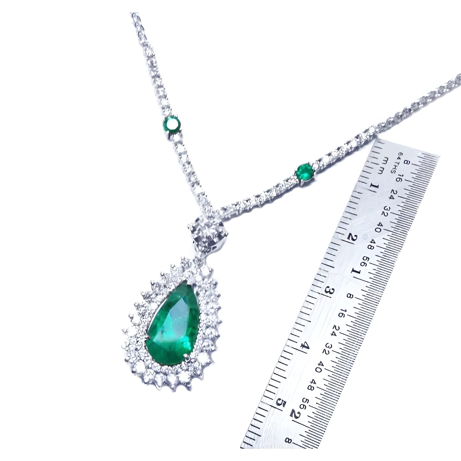 Pear cut emerald necklace with double diamond halo, set in 18K white gold, shown with ruler.