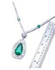 Pear cut emerald necklace with double diamond halo, set in 18K white gold, shown with ruler.
