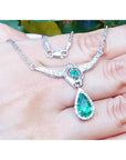 14K white gold necklace with a pear-shaped emerald pendant surrounded by diamonds.