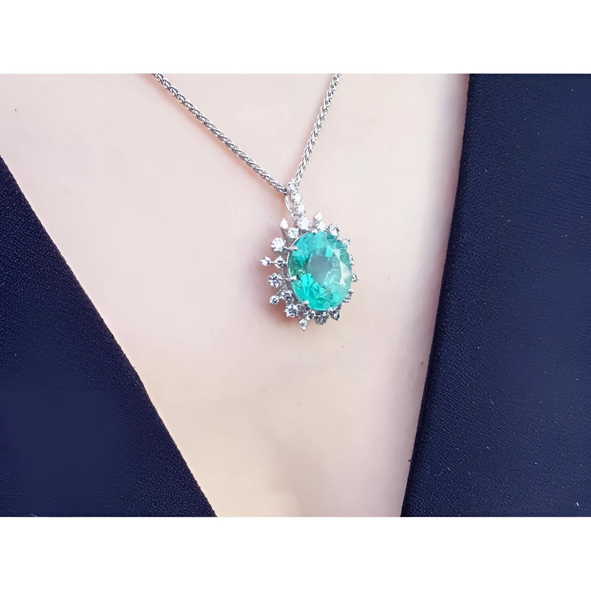 Oval cut medium light green emerald pendant with halo diamonds in 14K white gold on a chain.