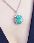 Necklace with a natural oval emerald pendant on a person's neck against a black background