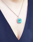 An oval emerald pendant necklace on a person wearing a dark blue dress.