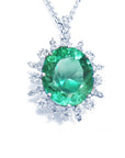 Emerald gemstone pendant with diamond accents showing top topside on a white background