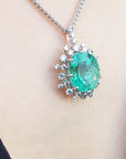 Emerald pendant necklace on a person's neck with a plain background