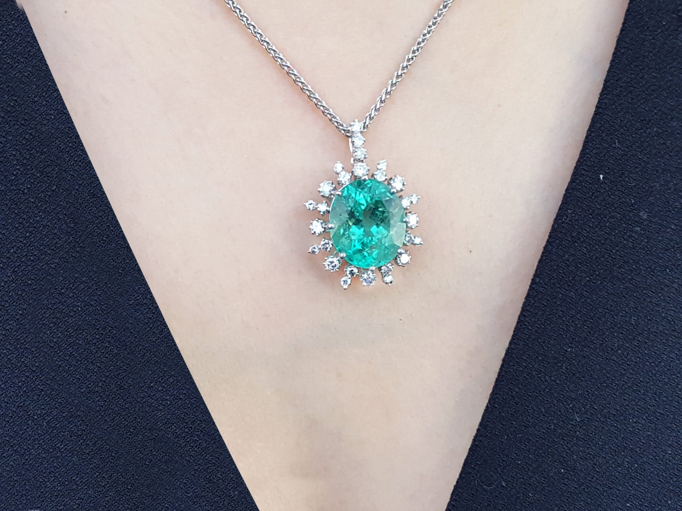Emerald pendant necklace on a person&#39;s neck against a black background