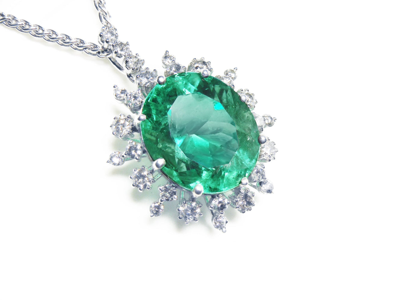 Emerald pendant with halo diamond accents in white gold on a topside position.