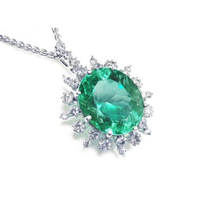 Emerald pendant with halo diamond accents in white gold on a topside position.