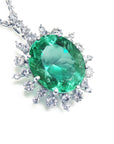 Emerald pendant with halo diamond accents in white gold on a topside position.