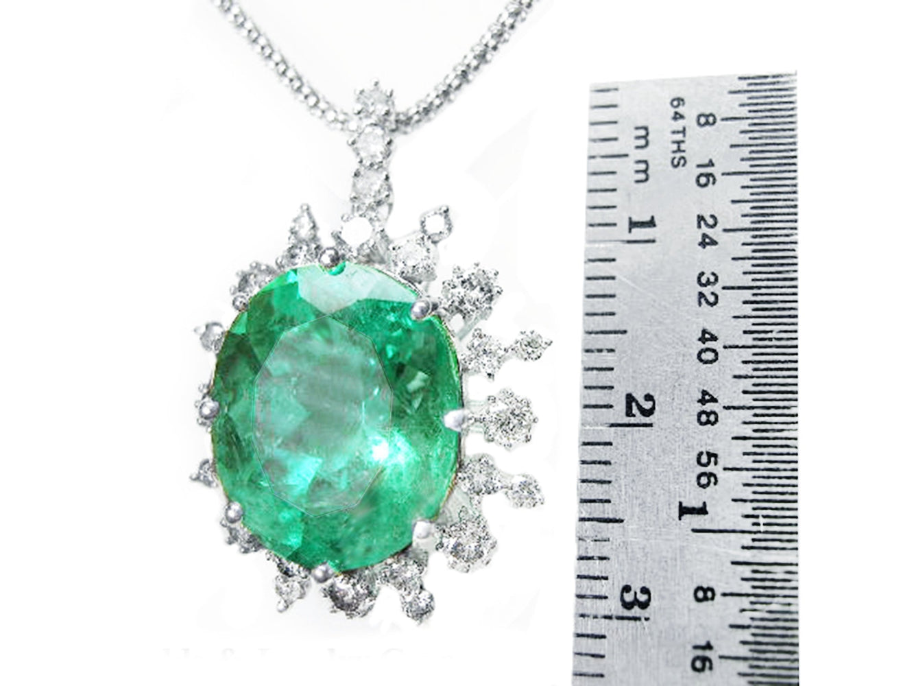 Emerald pendant with diamonds accent next to a ruler for size reference.