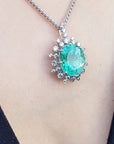 Emerald green gemstone pendant on a chain against a neutral background