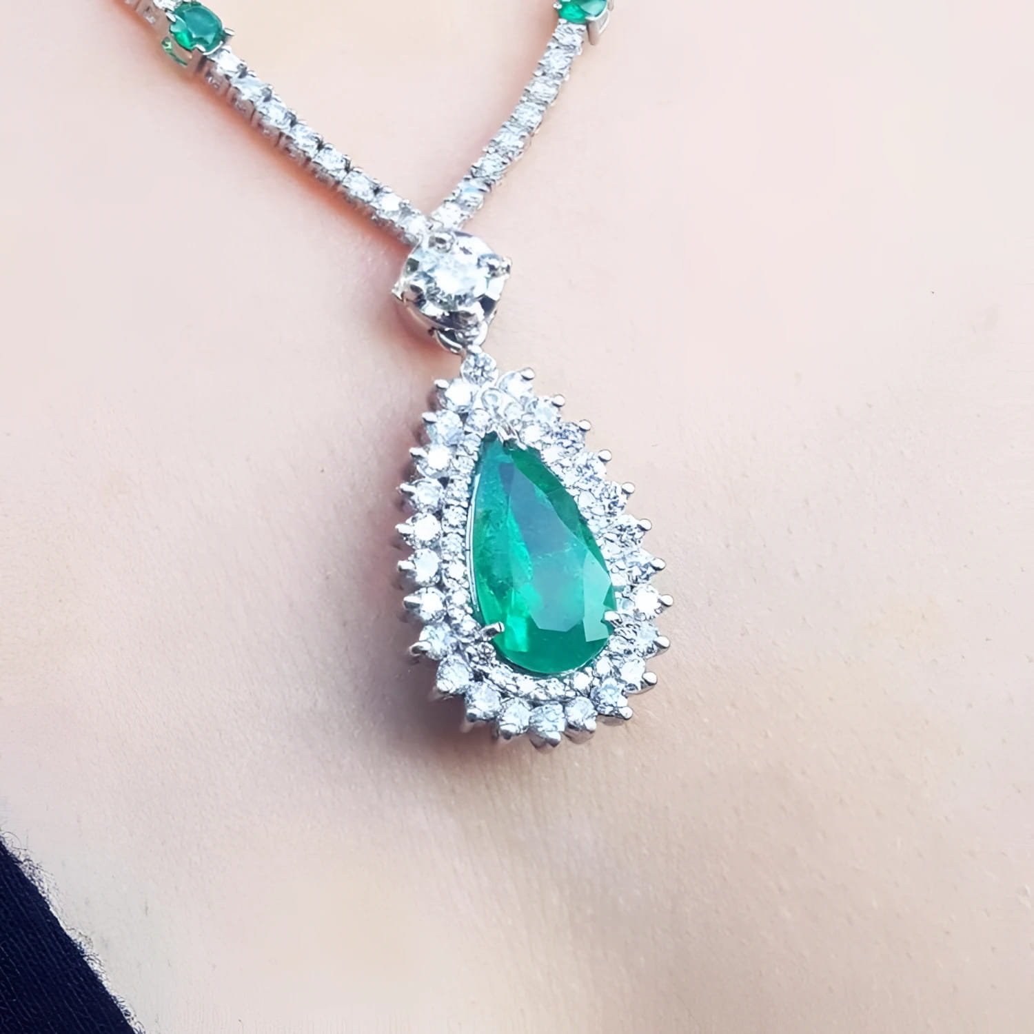 Pear cut emerald necklace with double diamond halo in 18K white gold.