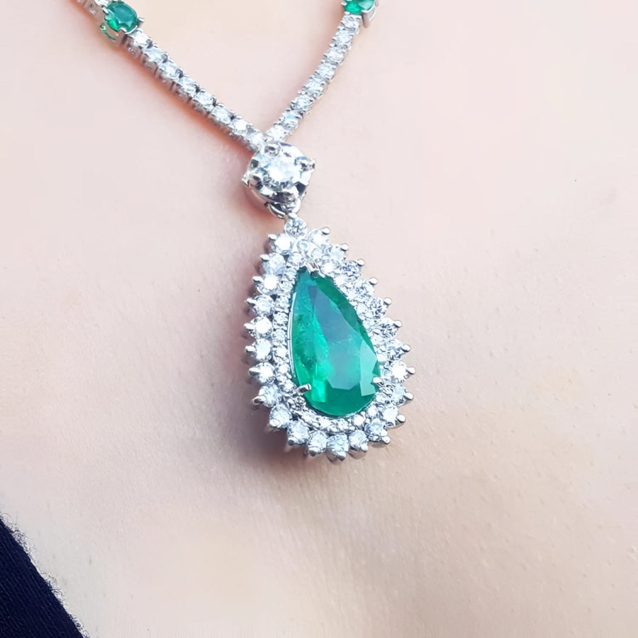 Pear cut emerald necklace with double diamond halo in 18K white gold.