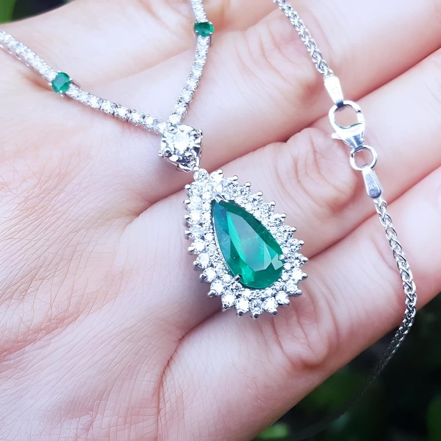 Pear cut emerald necklace with double diamond halo on 18K white gold chain.