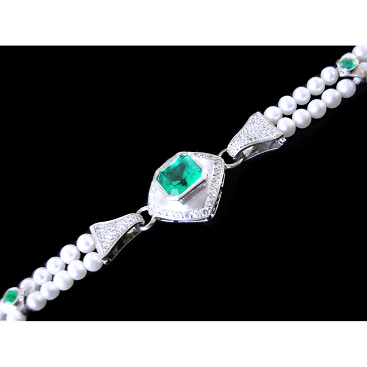 Pearl bracelet with a white gold and diamonds clasp featuring a genuine emerald on a black background.