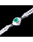 Pearl bracelet with a white gold and diamonds clasp featuring a genuine emerald on a black background.