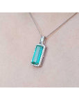Elongated natural emerald pendant with halo diamonds in 18K white gold on a chain.