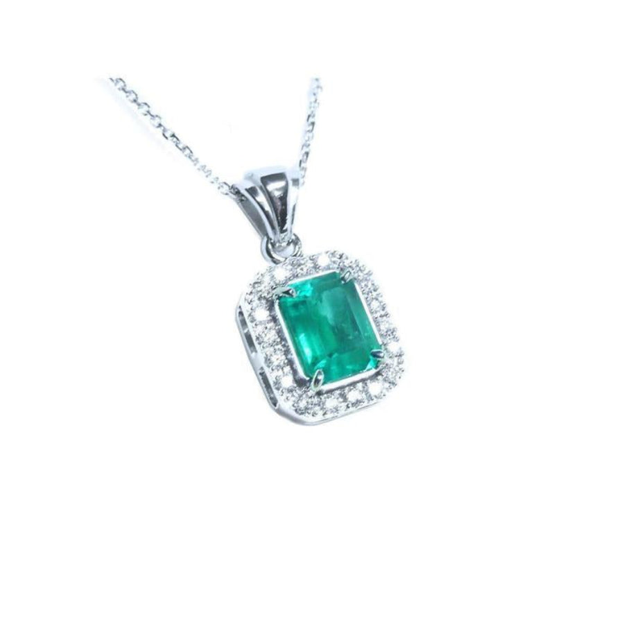 A natural emerald-cut colombian emerald pendant with a halo diamond accent made of 14k white gold.