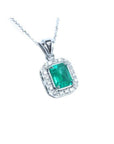 A natural emerald-cut colombian emerald pendant with a halo diamond accent made of 14k white gold.