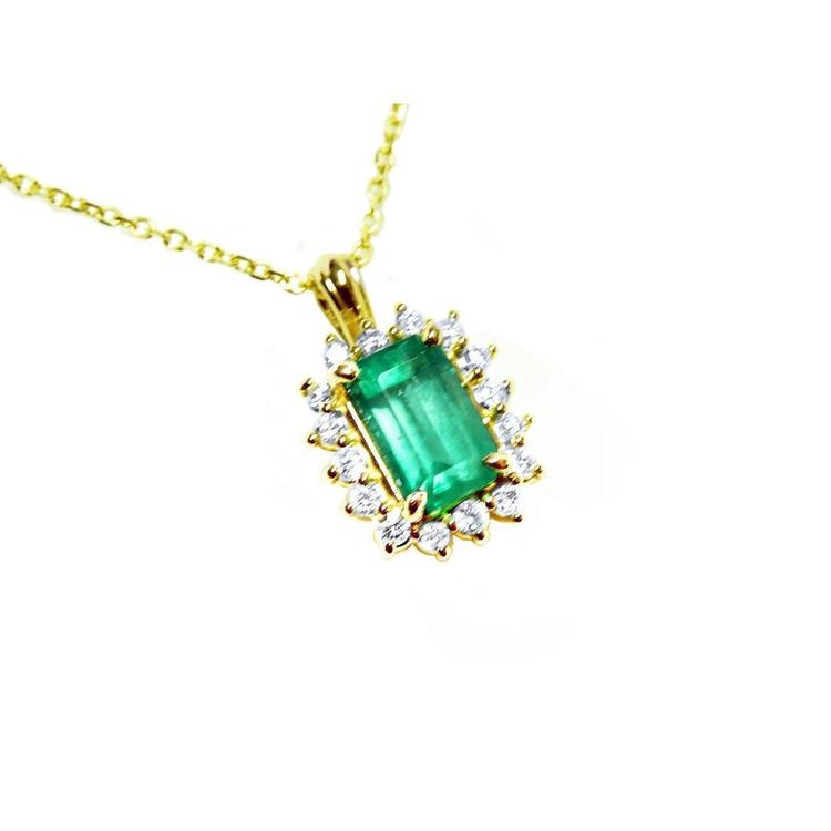 Gold necklace with a natural emerald and diamond accents on a topside view.