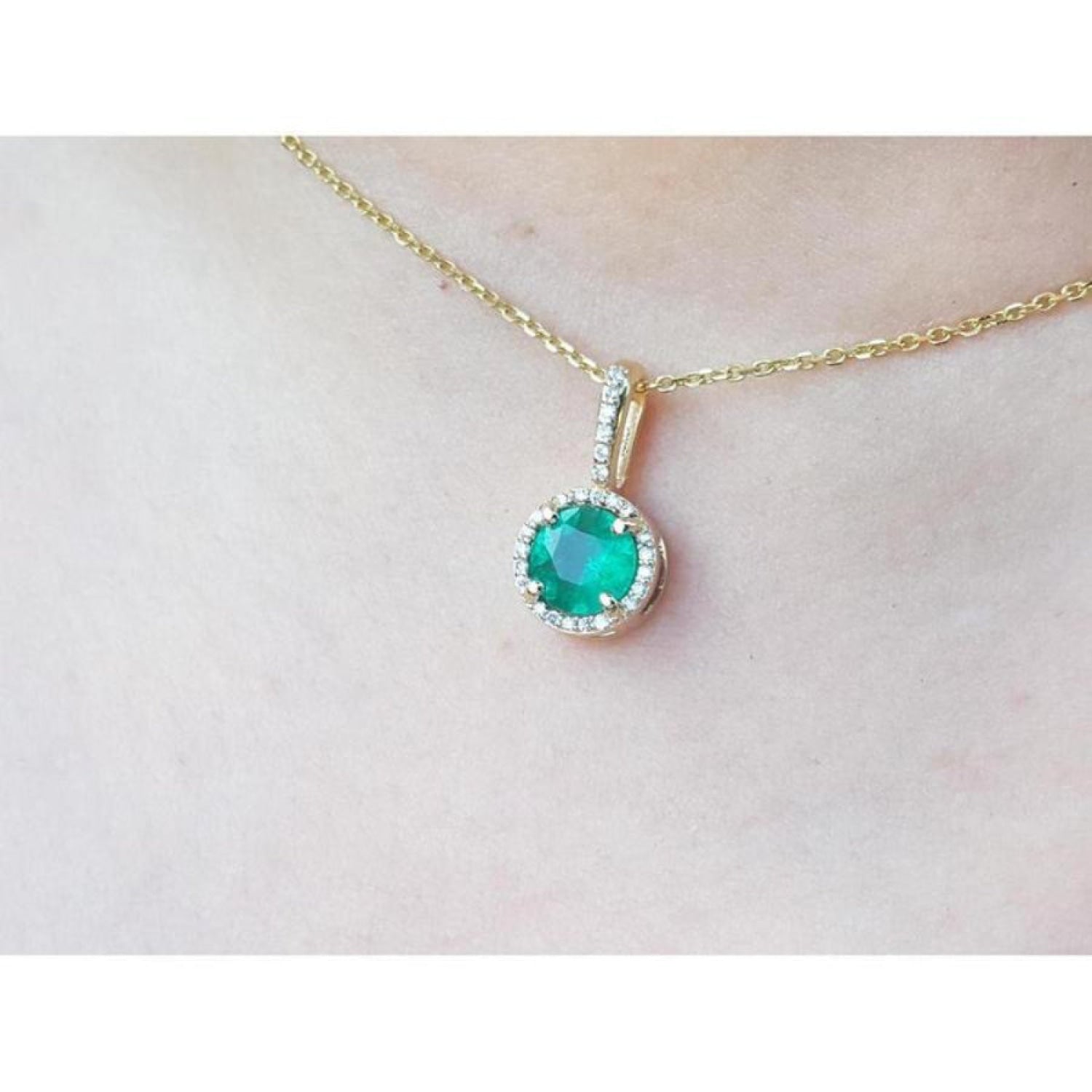 Round cut Colombian emerald pendant with halo diamonds on a 14K gold chain.