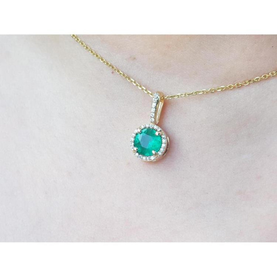 Round cut Colombian emerald pendant with halo diamonds on a 14K gold chain.
