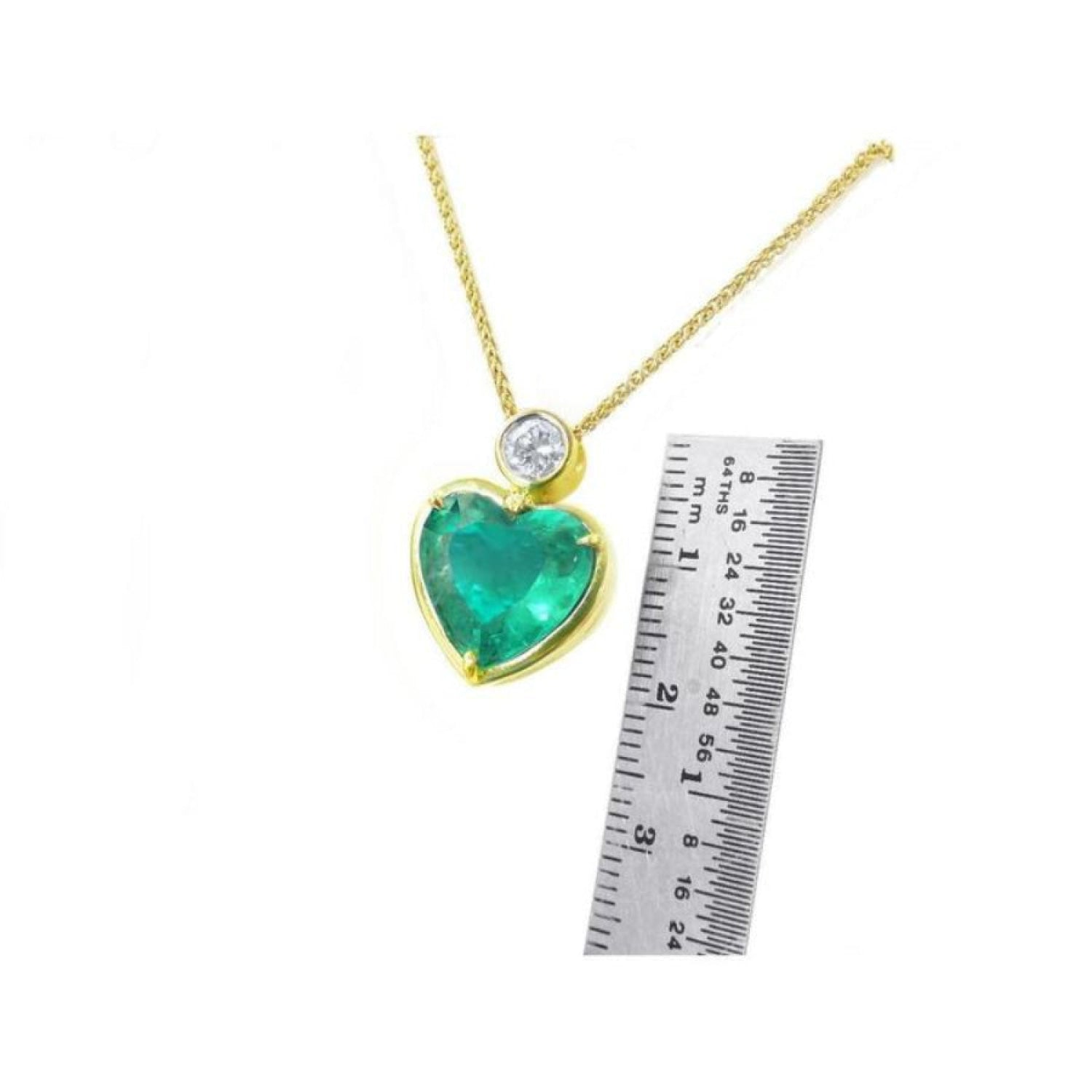 Heart-shaped emerald pendant necklace in 18K yellow gold with a diamond slider bail, shown with a ruler for scale.