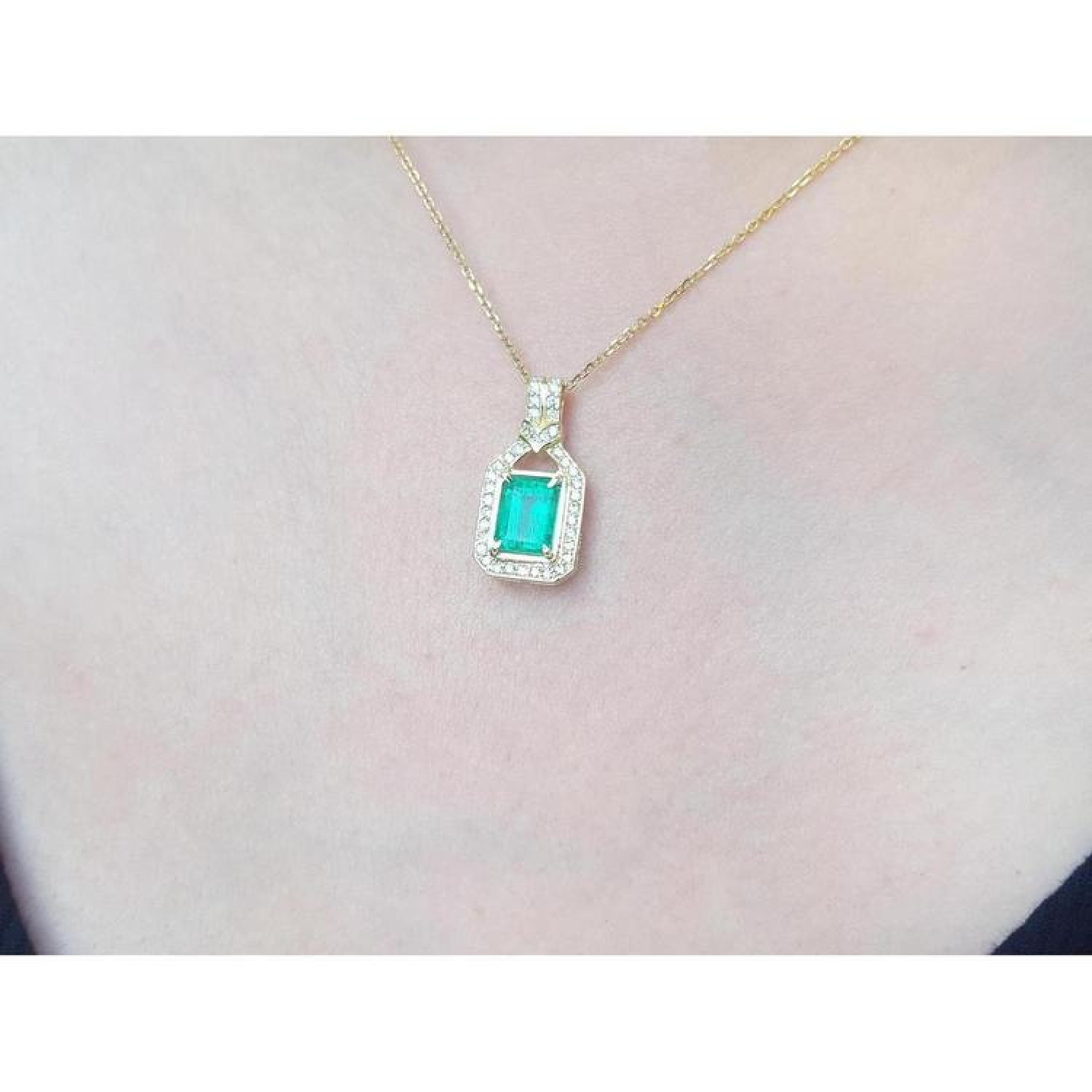2.06 ct. emerald and natural diamond pendant in 18K yellow gold, worn on a woman's neck.