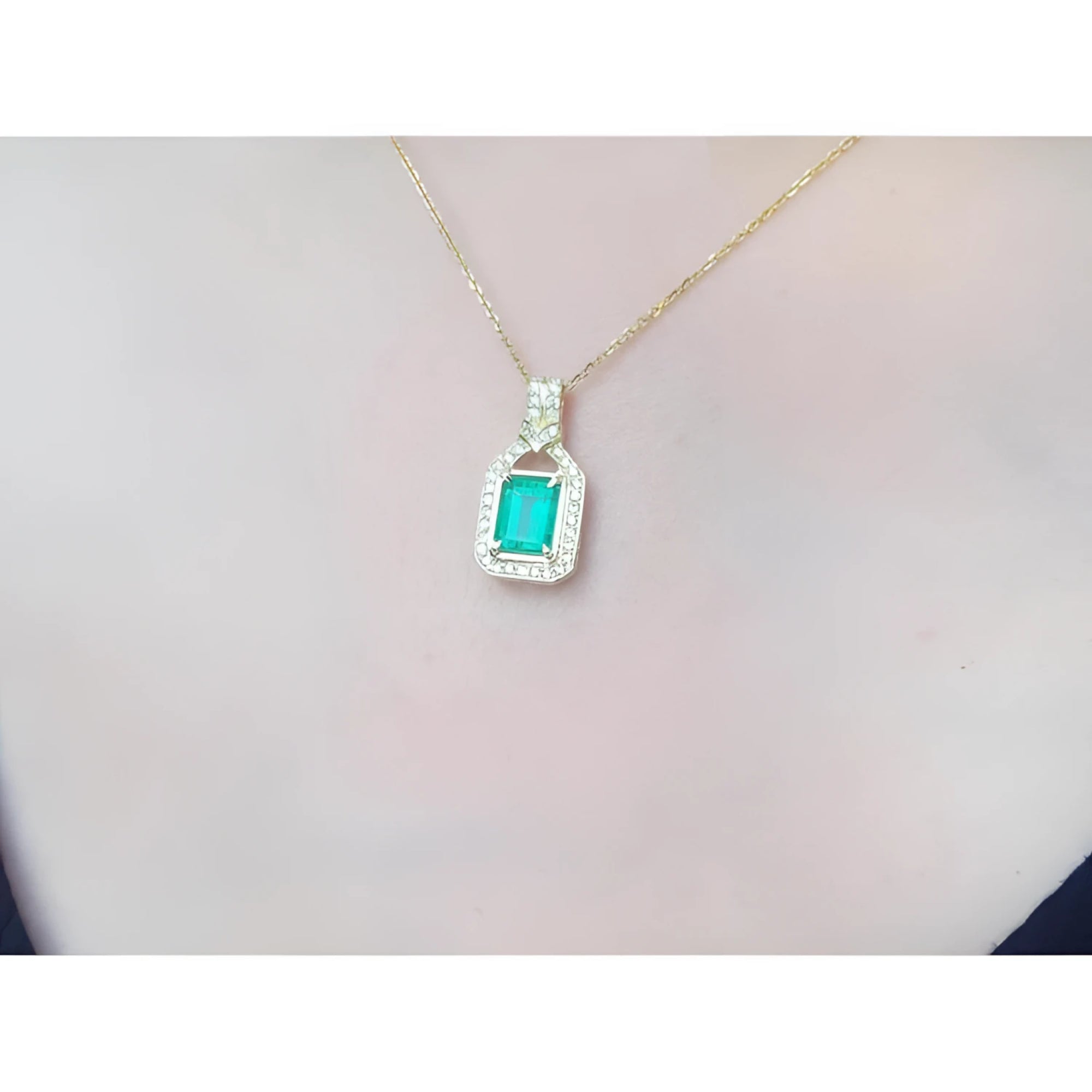 2.06 ct. emerald and natural diamond pendant in 18K yellow gold, worn on a woman's neck.