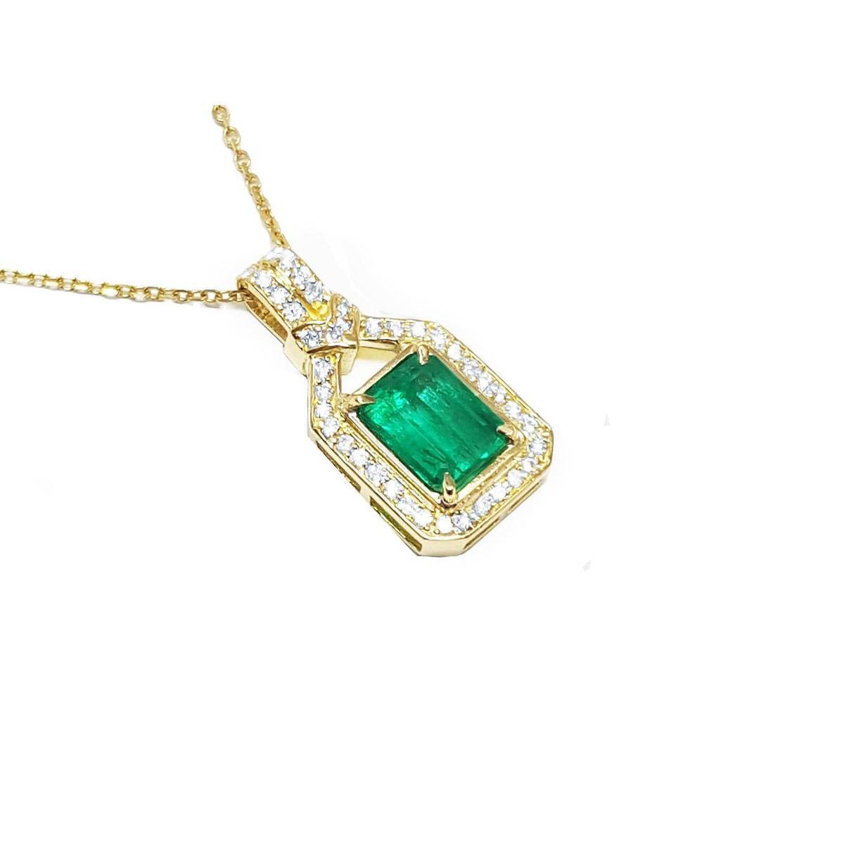 A 18k yellow gold emerald pendant with natural accent diamonds surrounding the square gemstone, toside view.