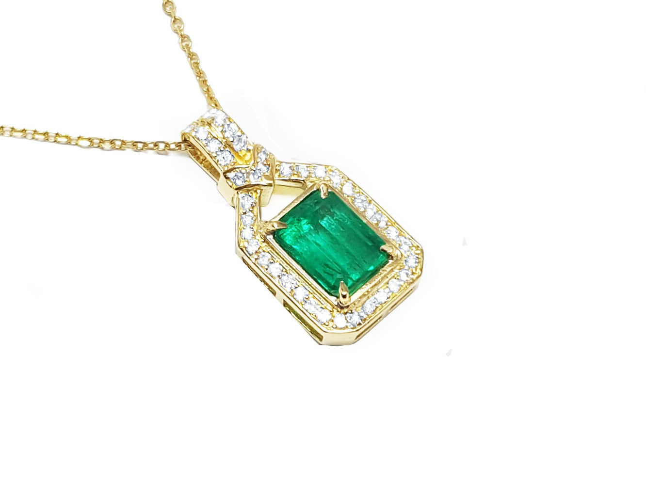 A 18k yellow gold emerald pendant with natural accent diamonds surrounding the square gemstone, toside view.