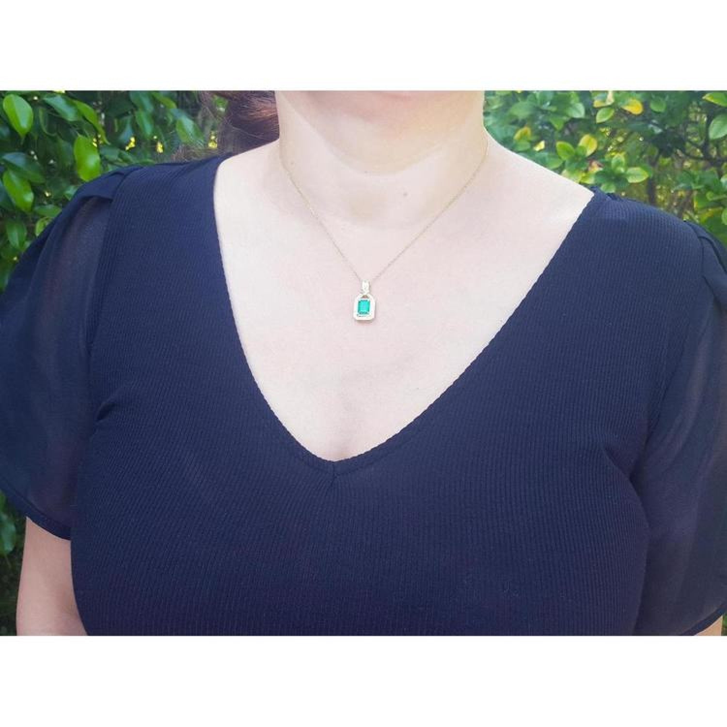 Emerald and diamond pendant in 18K yellow gold, worn on a woman's neck.