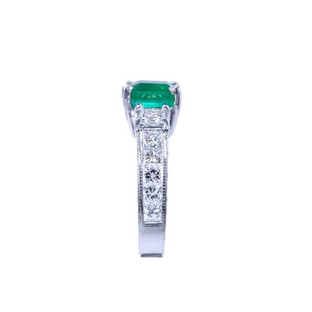The sparkling greenfire of this Colombian emerald ring on top and the side vibrant princess cut diamonds on the band are visibles.