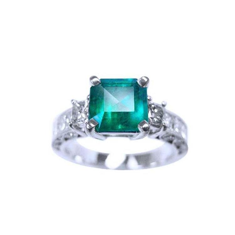A real colombian emerald ring with side princess cut diamonds crafted in 14k white gold.