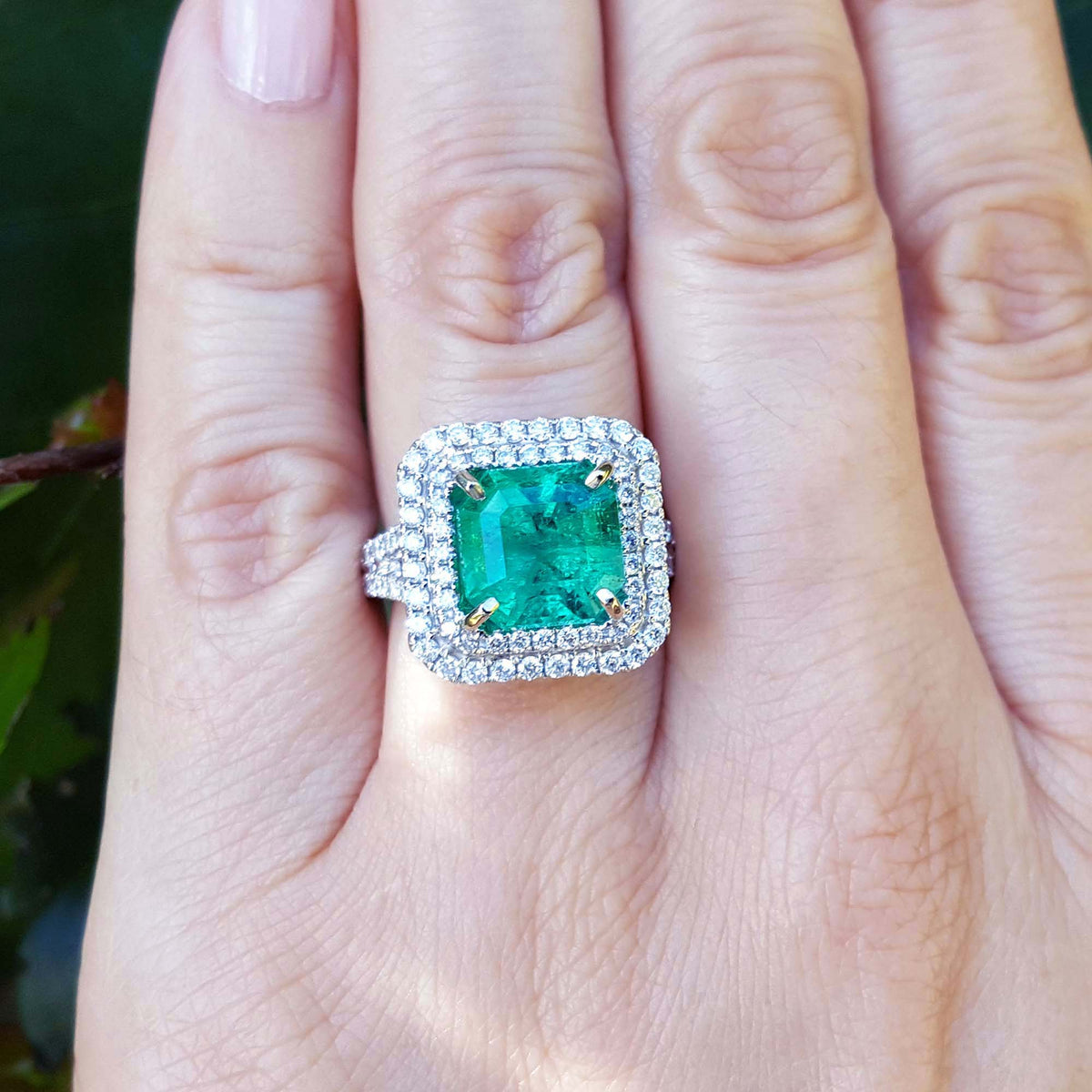 4.14 ct GIA F1 Colombian emerald ring with diamond halo and band in 14K white gold on a hand.