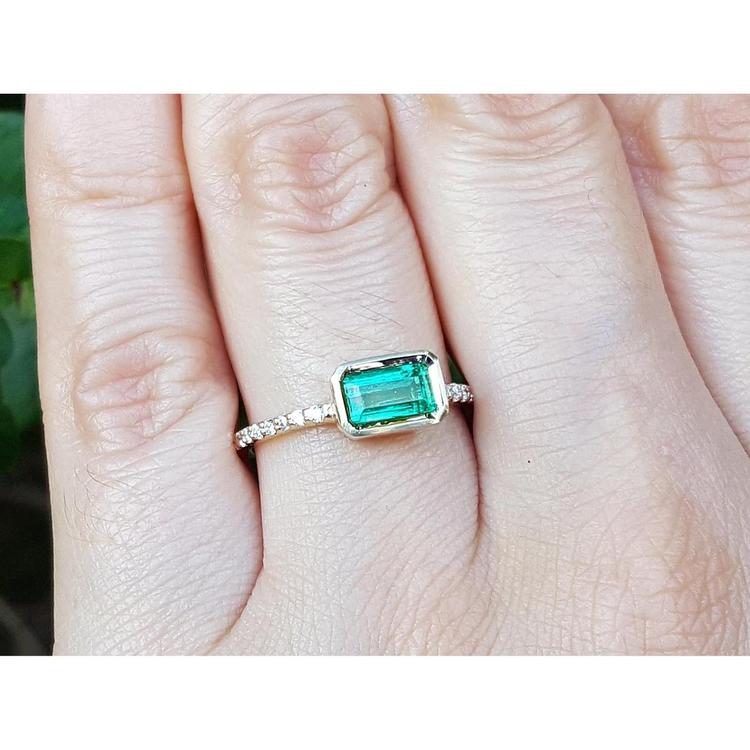 Emerald-cut bezel set natural colombian emerald ring in 14k yellow gold with accent diamonds.